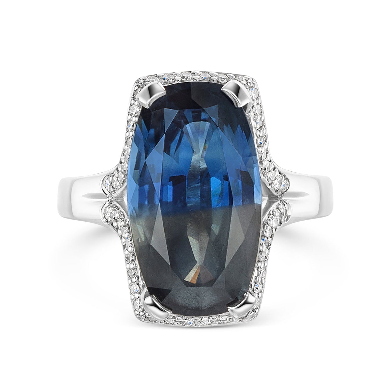 Parti sapphire in blue and grey tones, surrounded by a halo of round brilliant cur diamonds set in a platinum band on a white background
