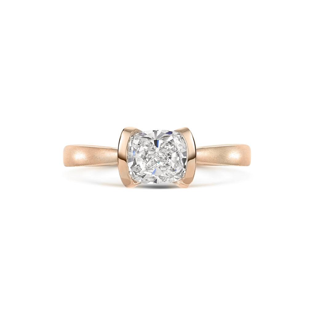 Cushion cut diamond solitaire engagement ring in rose gold on a white background