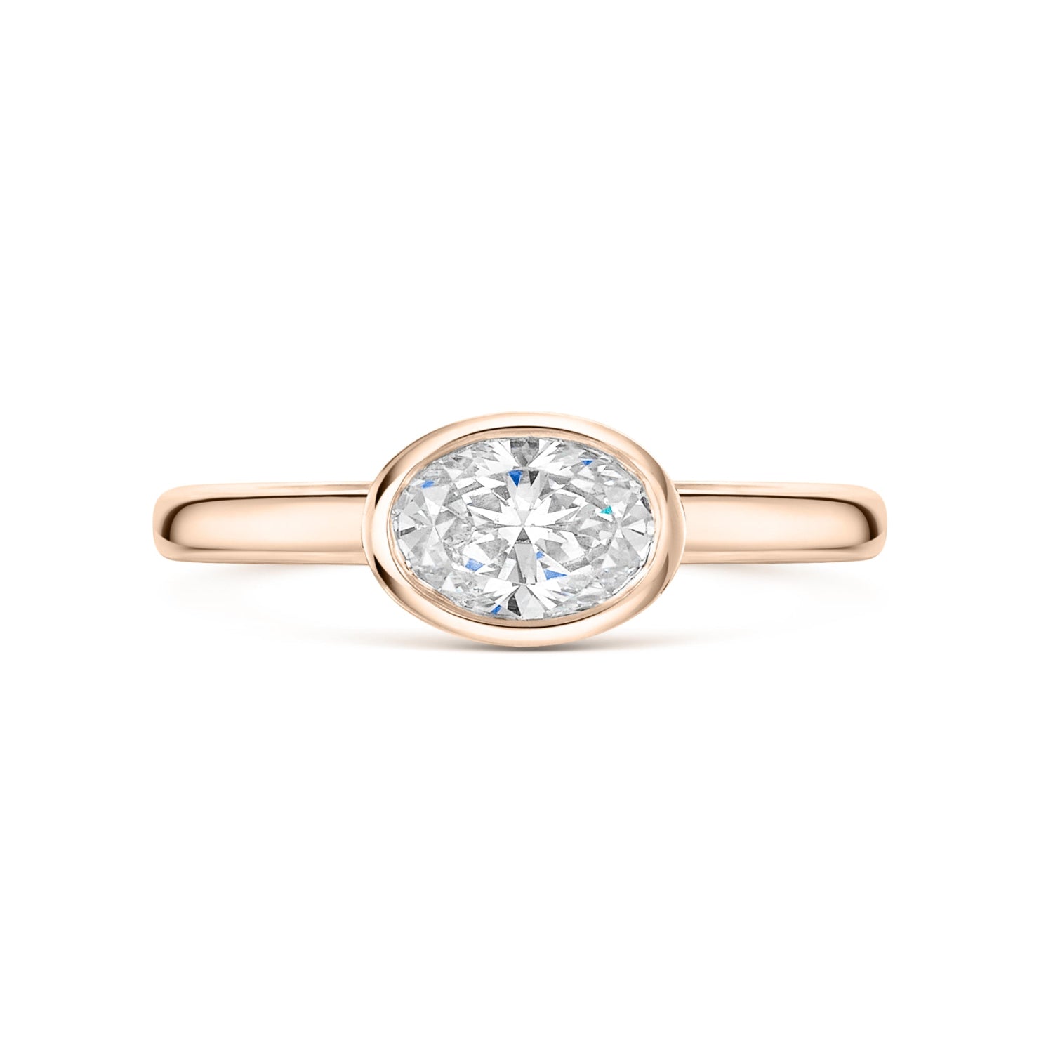 East West bezel set oval diamond solitaire in rose gold on a white background