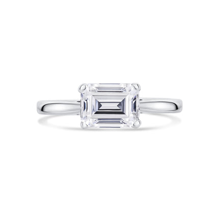 Diamond ring with emerald-cut diamond set across on a white background