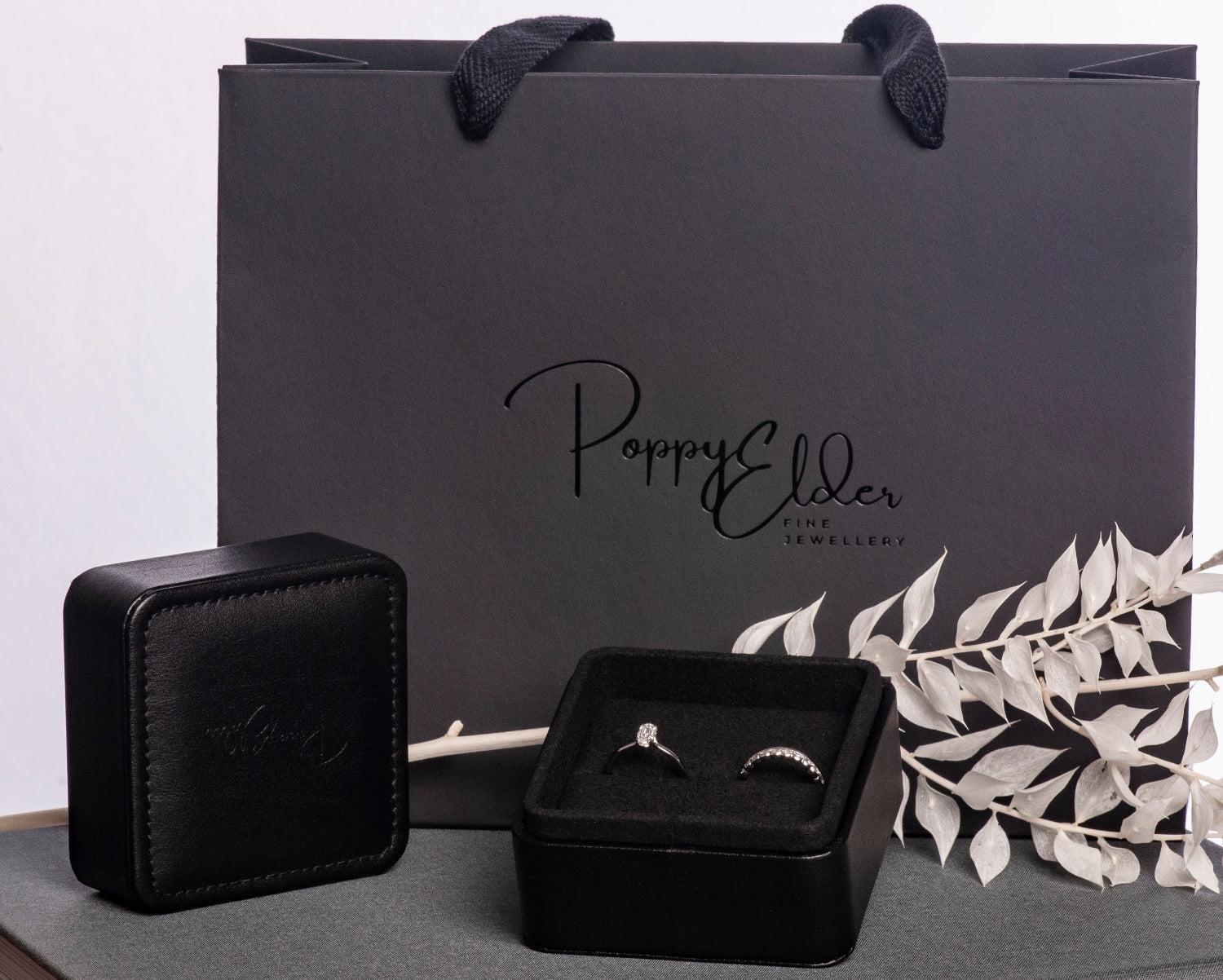 Bespoke Bridal Jewellery box with rings on a book next to a branded black bag