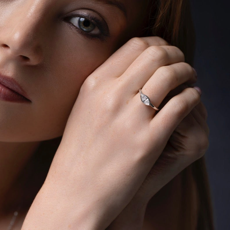 Close-up of a woman's hand wearing a Marquise East West Bezel Solitaire diamond ring on a dark background