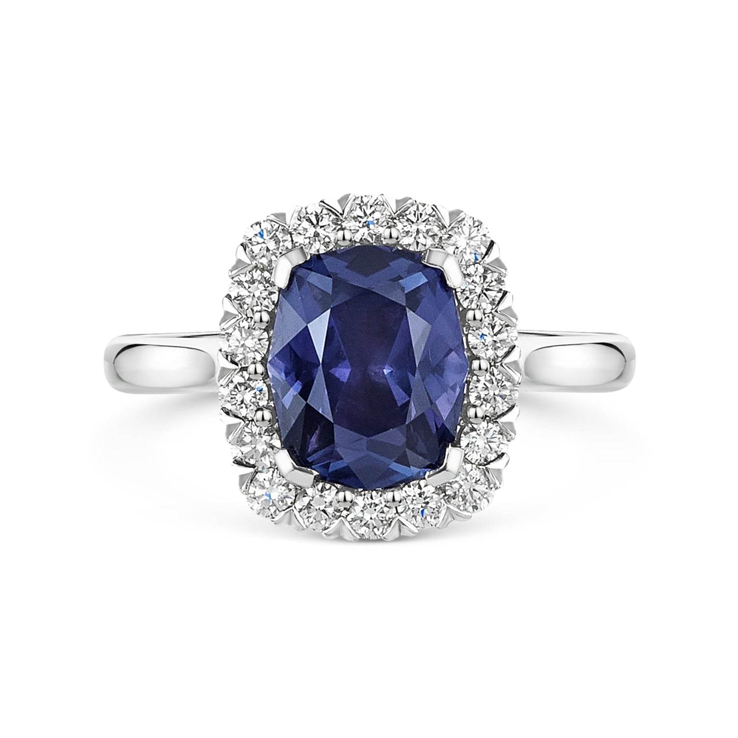 A silver-tone halo ring featuring a large, cushion-cut deep blue purple colour change sapphire center stone surrounded by a halo of small white diamonds, set against a plain white background.