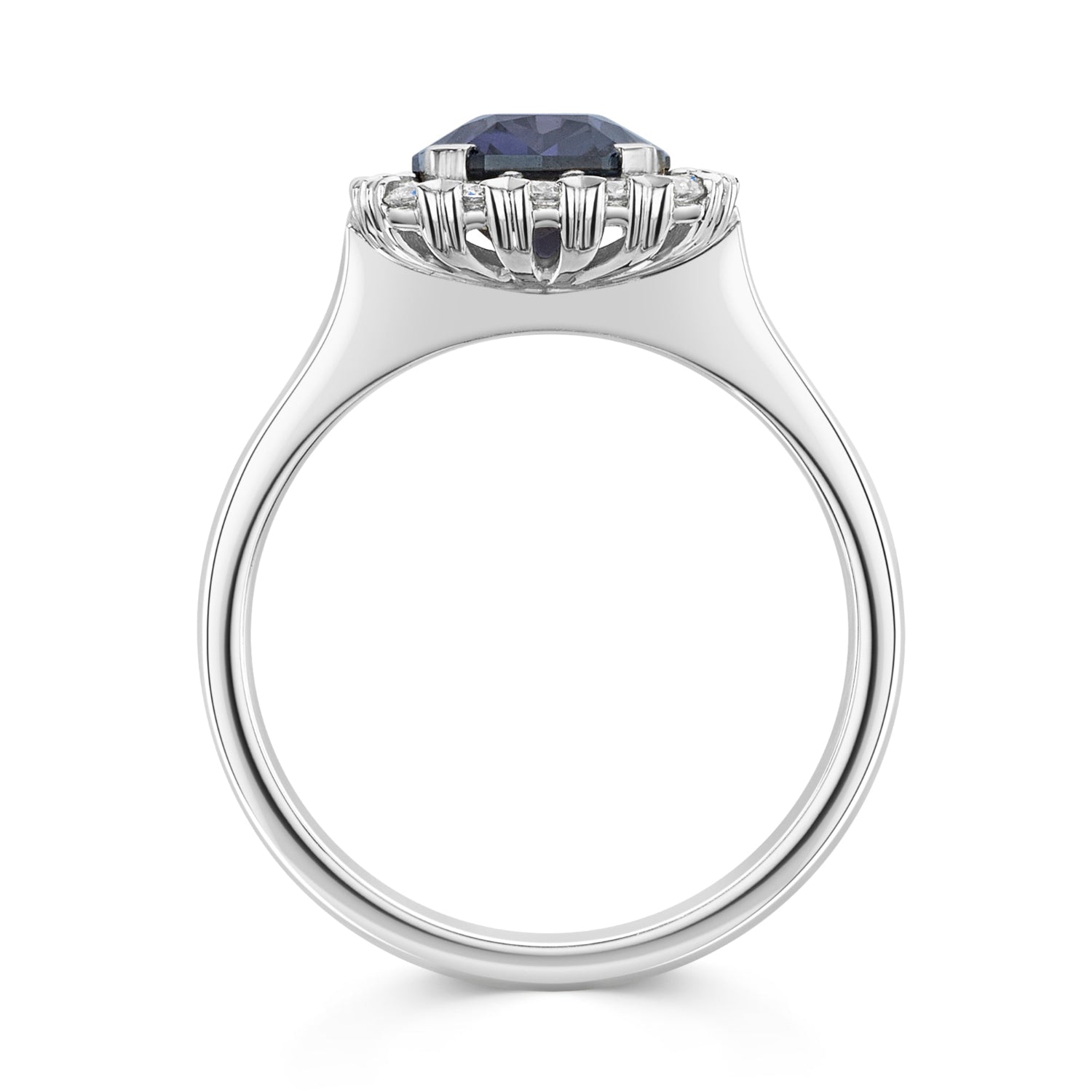 A silver-tone halo ring featuring a large, cushion-cut deep blue purple colour change sapphire center stone surrounded by a halo of small white diamonds, set against a plain white background - side view
