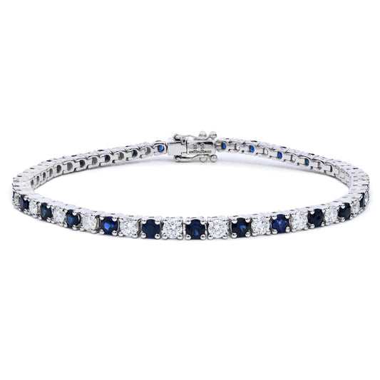 Sapphire and diamond tennis bracelet with alternating diamonds and blue sapphires in claw setting on a white background.