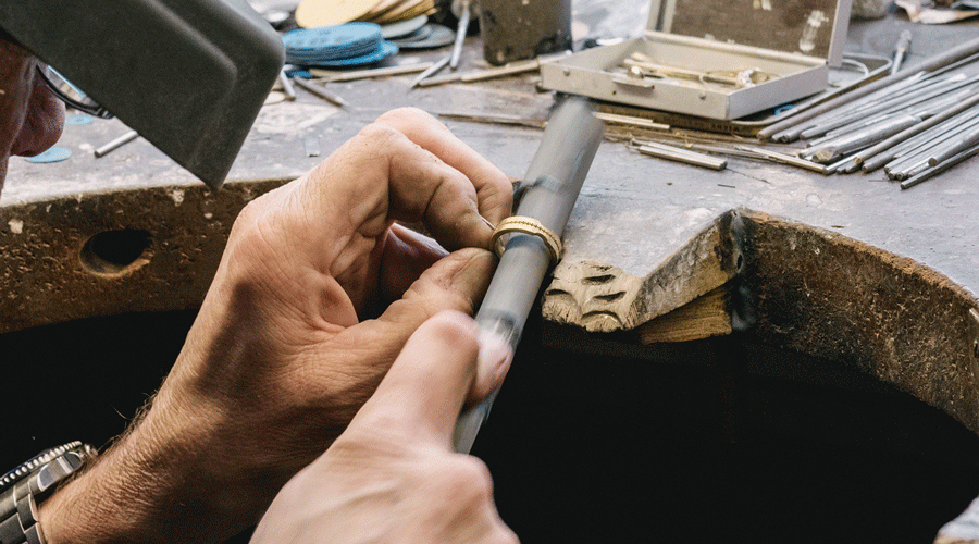 goldsmith working on the bench on a gold ring with tools 