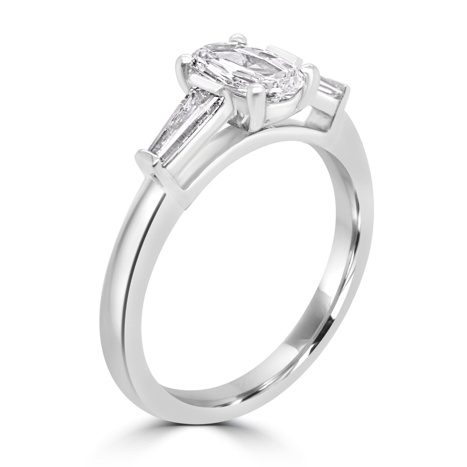 step cut oval diamond trilogy ring with tapered baguettes - angled view on white background