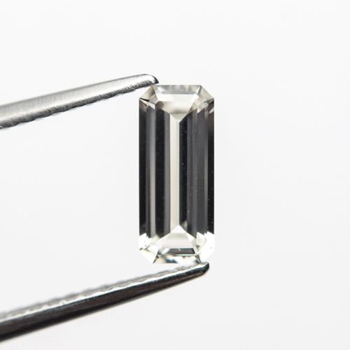 0.71ct White Sapphire Elongated Emerald Cut Loose Stone held by tweezers