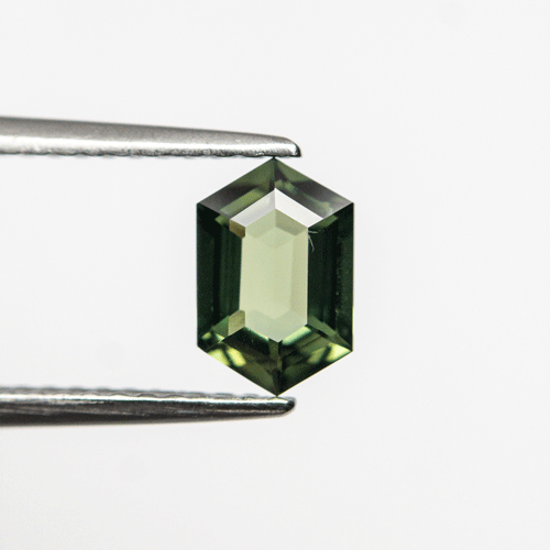 0.87ct Green Sapphire in Hexagonal Shape in tweezers.