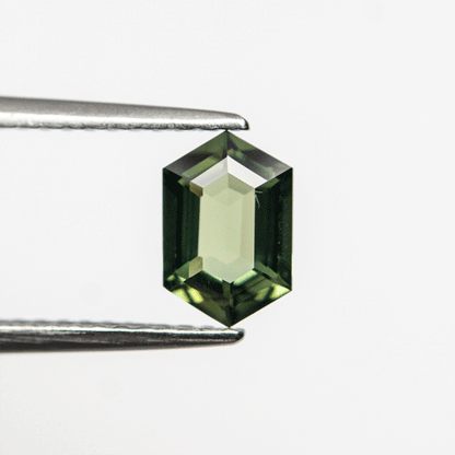 0.87ct Green Sapphire in Hexagonal Shape in tweezers.